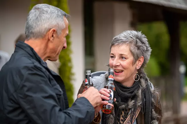 2 Personen trinken fröhlich vor der Tourist-Information Weinschorle
