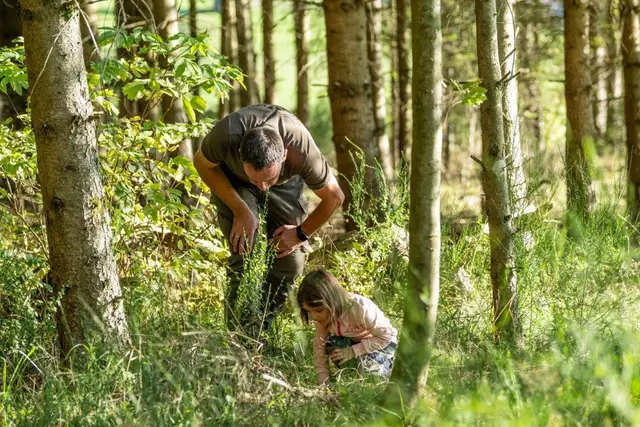 Der Jäger Fabian sucht mit einem Kinder nach Spuren auf dem Waldboden
